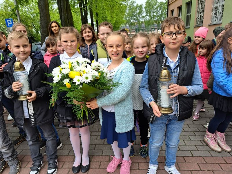 Na zdjęciu mali uczniowie składają kwiaty i znicze z okazji Dnia Patrona szkoły nr 12 - Jana Pawła II