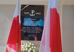Na zdjęciu tablica pamiątkowa na budynku Państwowej Szkole Muzycznej poświęcona Polakom pomordowanym przez Gestapo. Obok tablicy biało-czerwone flagi i kwiaty